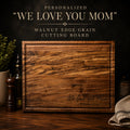 Personalized walnut cutting board engraved with We Love You Mom message

